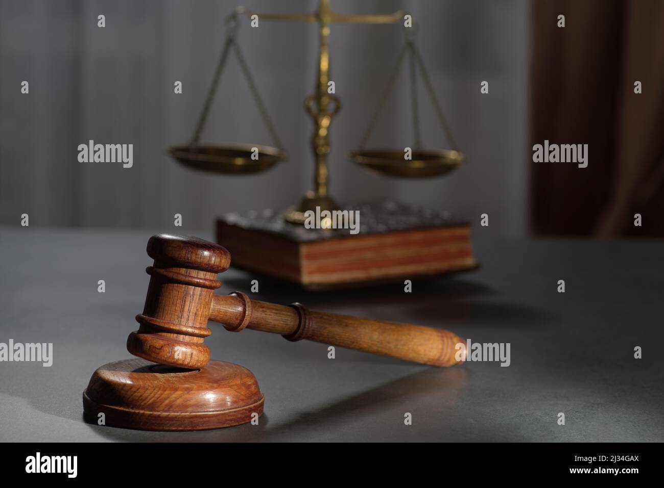 Los jueces de madera gavel y símbolo de la ley y la justicia sobre la mesa en una sala de audiencias o en una oficina de aplicación de la ley sobre fondo oscuro Foto de stock
