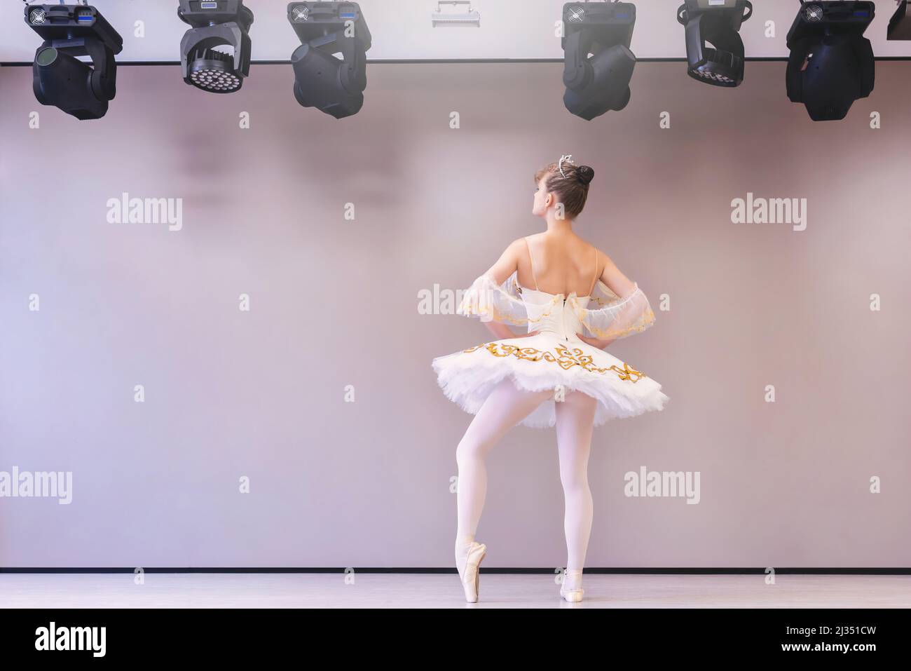 backview de la joven bailarina de ballet caucásica practica posiciones de ballet en falda tutu profesional de cisne blanco Foto de stock