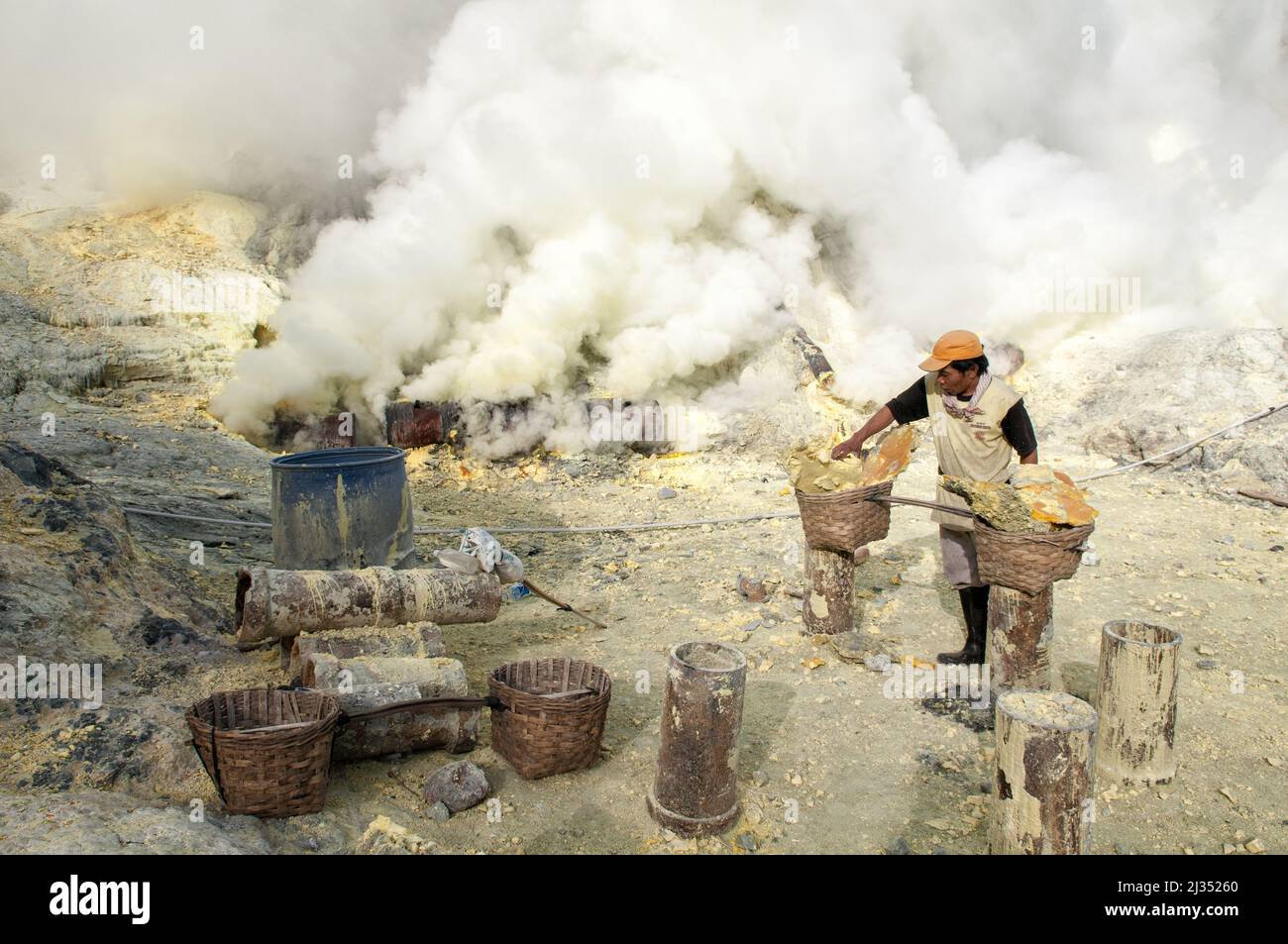 Minero llenando sus cestas con azufre en el volcán Ijen, Isla Java, Indonesia Foto de stock