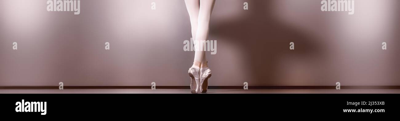una vista panorámica desde la parte trasera de las hermosas piernas y pies en los dedos vestidos con zapatos pointe de una joven bailarina Foto de stock