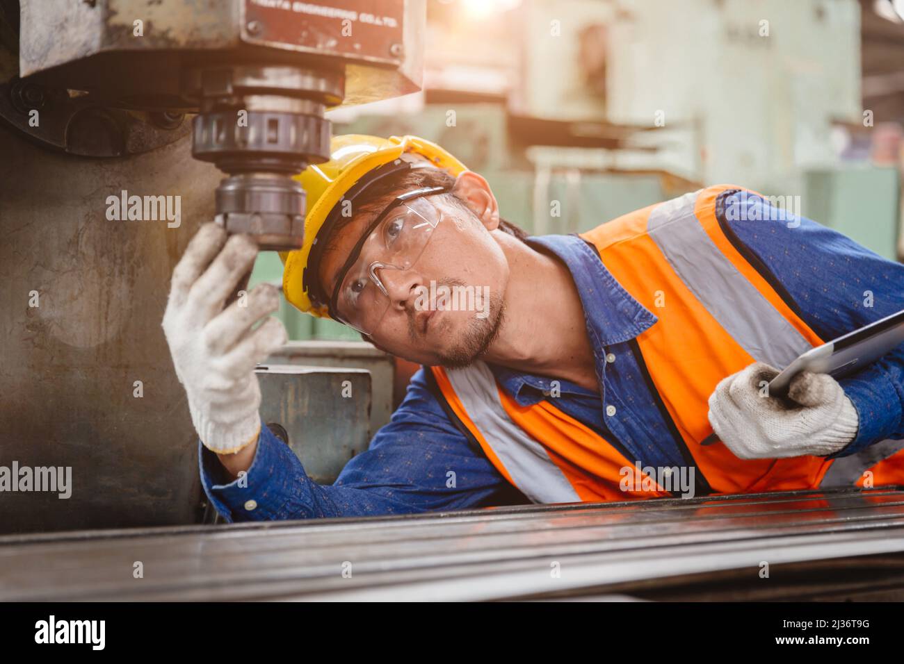 Personal técnico encargado de la instalación comprobar el estado del cabezal de perforación de la máquina CNC para la seguridad en el lugar de trabajo de la industria metalúrgica. Foto de stock