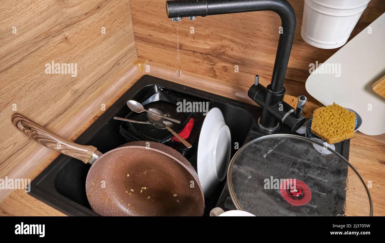 Montones de platos sucios en el fregadero y el grifo roto gotea Fotografía  de stock - Alamy