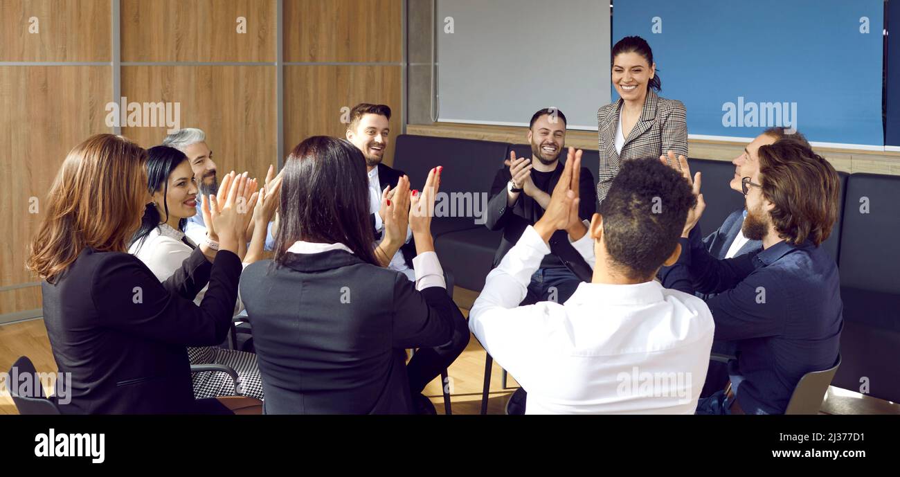 Un grupo de empleados satisfechos se aferran a las manos para dar reconocimiento al líder de su equipo Foto de stock