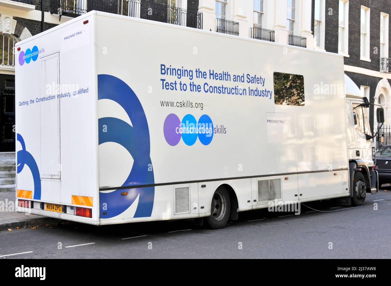 Camión de carrocerías rígido estacionado y conectado a oficinas que llevan las pruebas y habilidades de salud y seguridad a la industria de la construcción en Londres Inglaterra Reino Unido Foto de stock