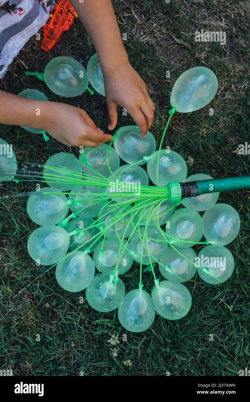 niños llenando globos de agua verde en el verano, diversión en el patio  trasero Fotografía de stock - Alamy