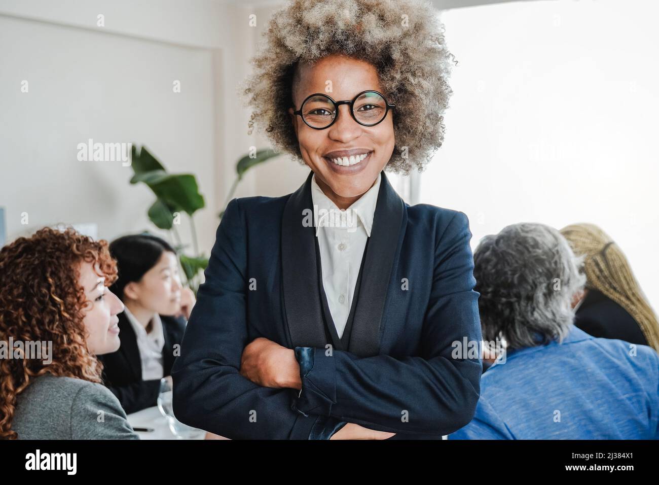 Mujer de negocios africana que trabaja en una oficina bancaria moderna con colegas en el fondo - Foco en la cara Foto de stock