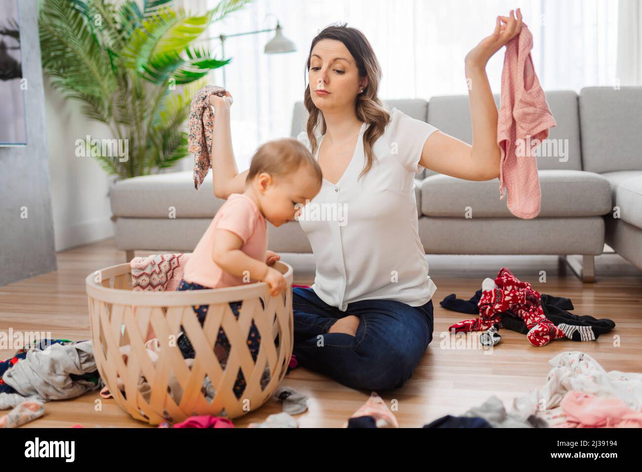 la mujer tiene problemas para elegir ropa con el bebé en la sala de estar  Fotografía de stock - Alamy