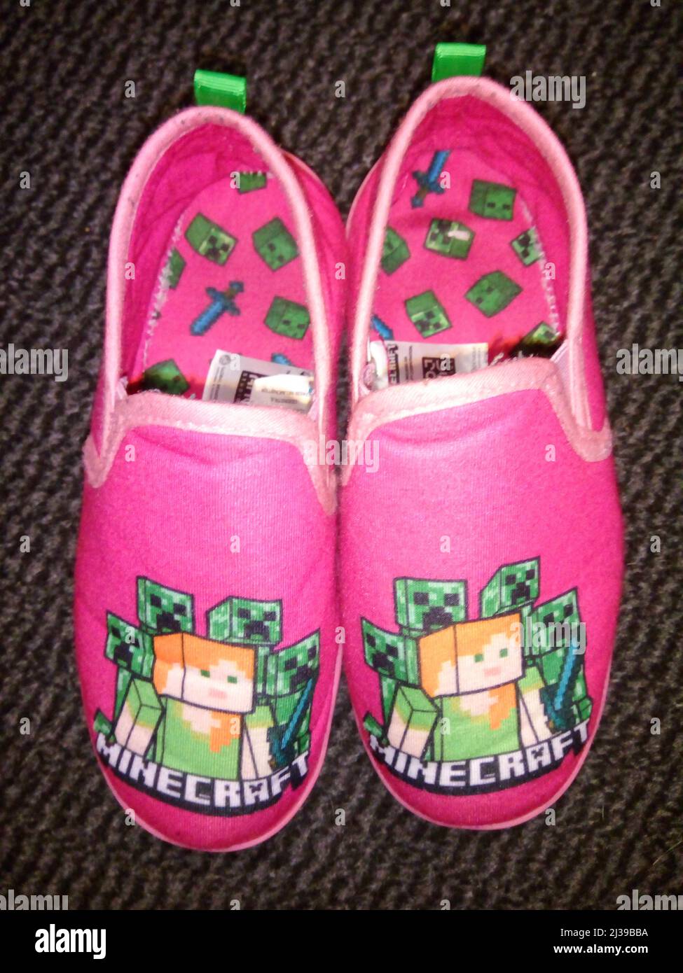 Zapatillas de Minecraft rosas para niños sobre un fondo oscuro. 06-04-2022, Lancashire, Reino Unido Foto de stock