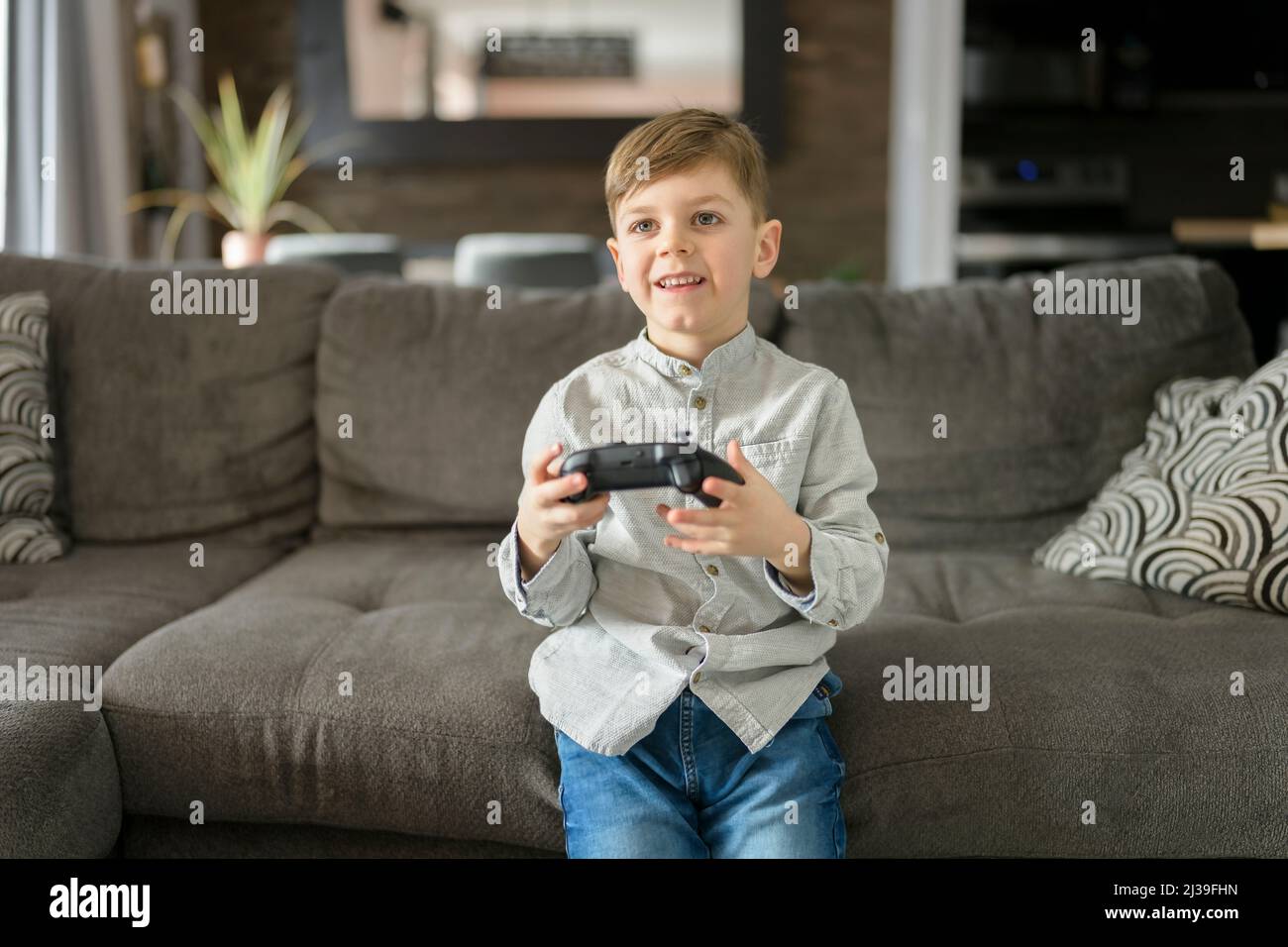 6 años niño paly juego de vídeo en el sofá en casa Foto de stock