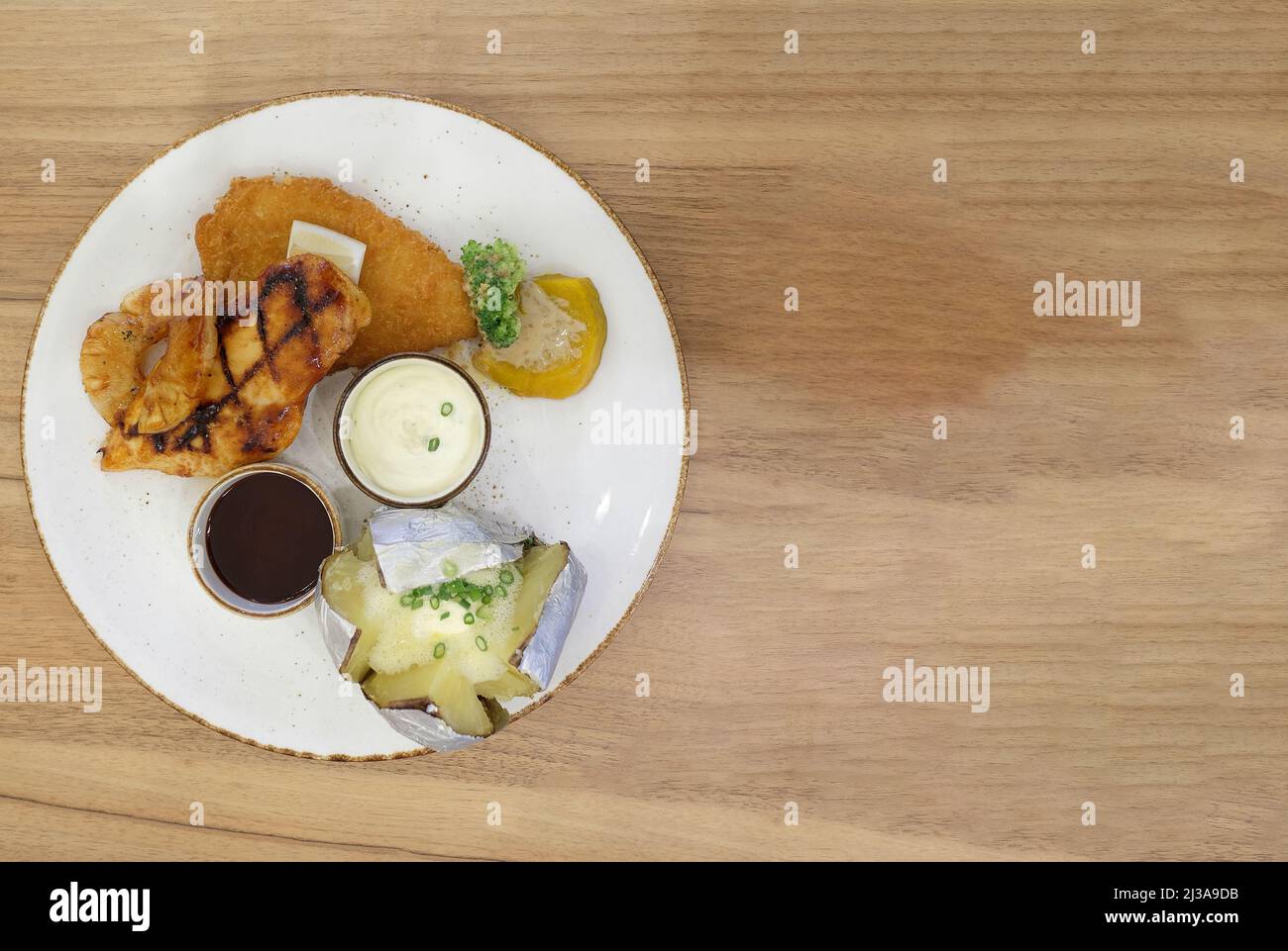 Juego de filetes de pollo en un plato blanco se coloca en un piso de madera marrón y tiene espacio para copiar. Foto de stock
