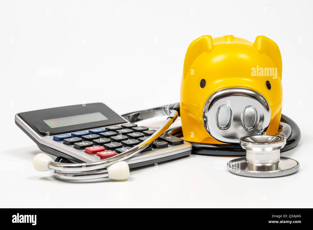 Concepto de gastos médicos con banco piggy, calculadora y estetoscopio Foto de stock
