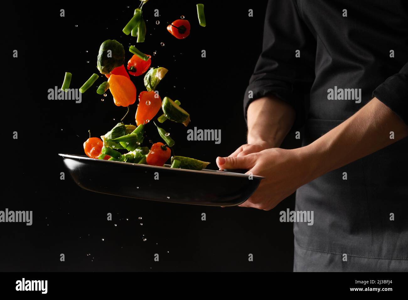 Cook prepara verduras sobre un fondo negro, cocina oriental, comida sabrosa  y saludable, libro de recetas, menú, cocina Fotografía de stock - Alamy