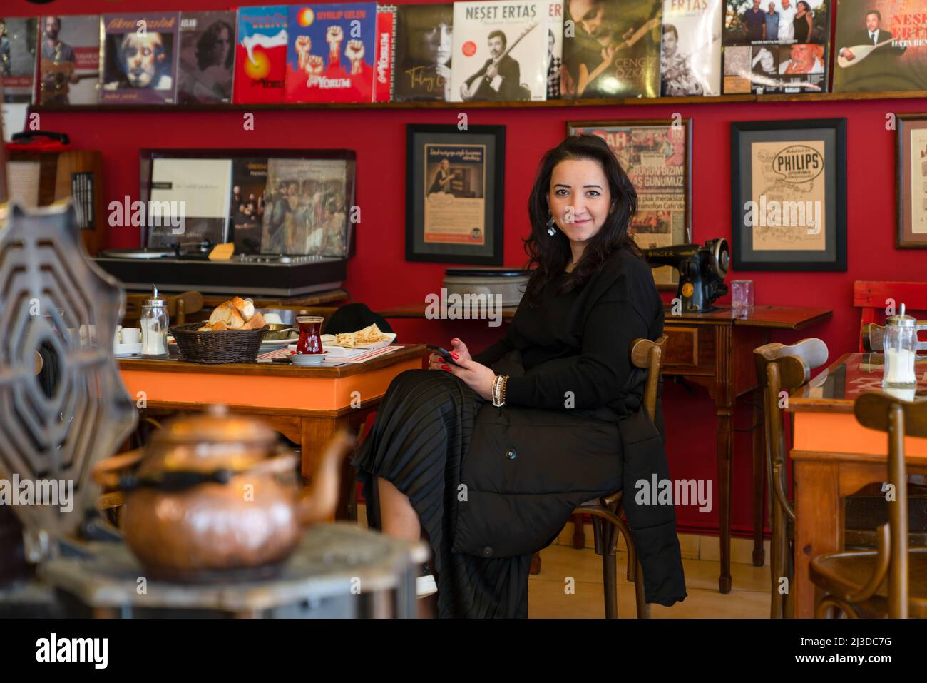 Ankara, Turquía - 26 2022 de marzo: Una mujer cliente tomando té y desayuno en una cafetería turca con estufa de calefacción. Foto de stock