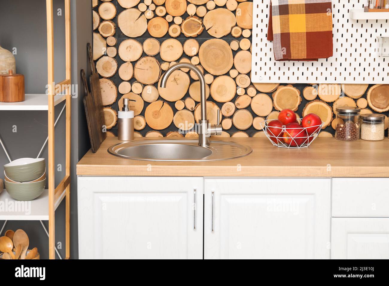 Mostrador de madera con fregadero de plata, jabón para platos y cesta de  manzanas cerca de la pared de madera en la cocina Fotografía de stock -  Alamy