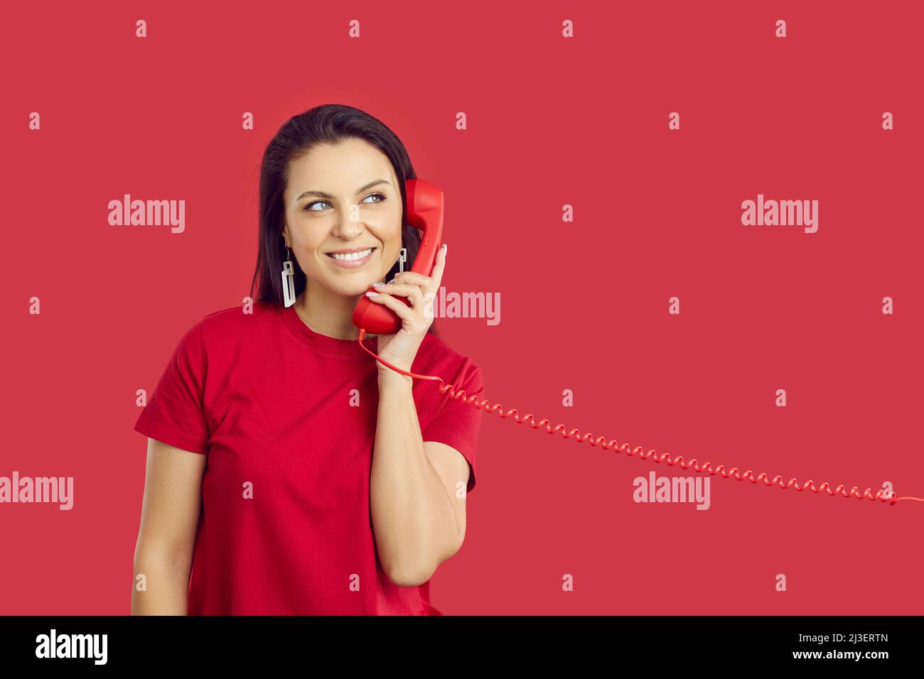 Una mujer sonriente habla por teléfono fijo Foto de stock