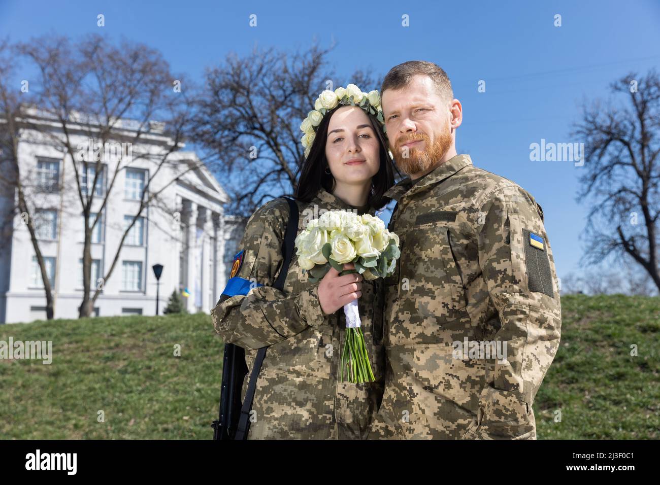 Los recién casados con uniforme militar con ametralladoras y un ramo de  bodas posan para una foto memorable en su día de boda. Miembros de la  Defensa Territorial de Kiev, Anastasiia Mokhina,