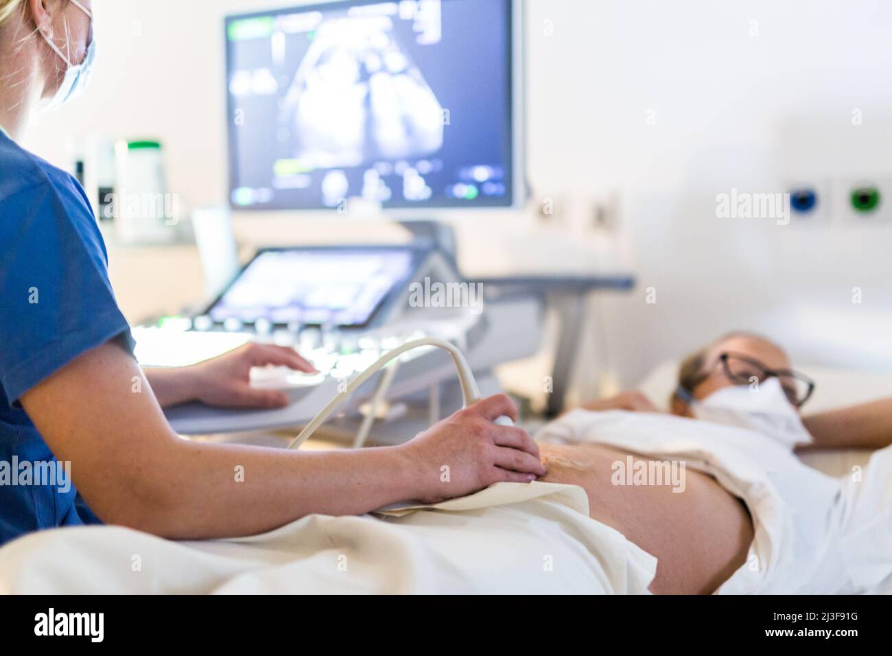 Primer plano de una mujer embarazada que se le realiza una ecografía en la clínica médica. Concepto de salud y medicina Foto de stock