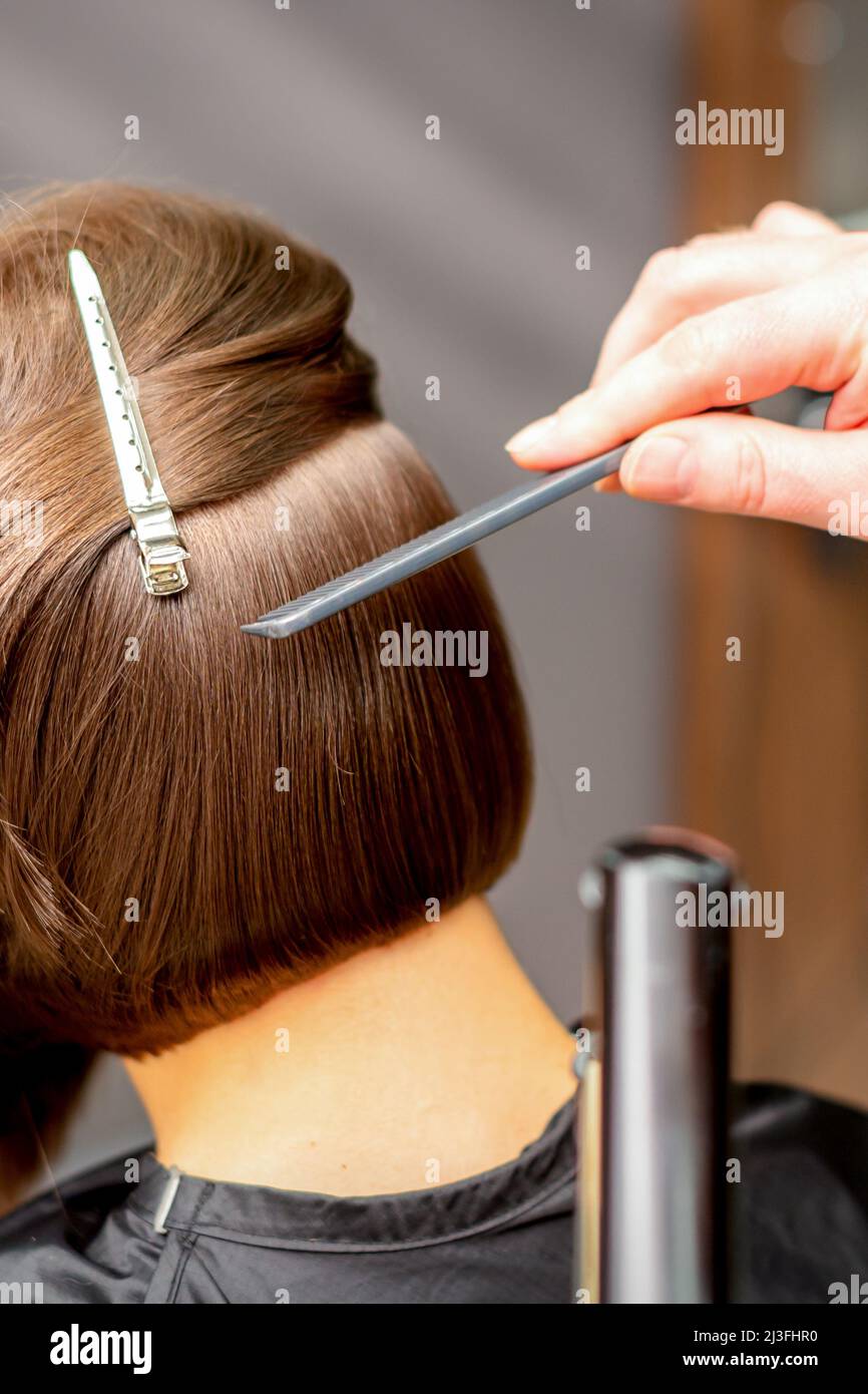El estilista es alisar el pelo corto de la mujer joven de brunette con una  plancha plana en un salón de la peluquería, cerca para arriba Fotografía de  stock - Alamy