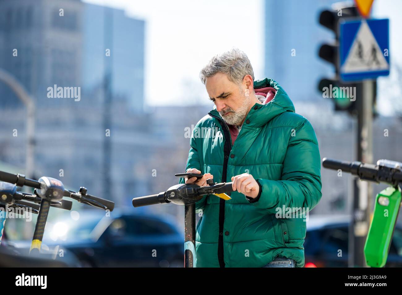Hombre maduro que activa el scooter eléctrico desde el smartphone Foto de stock