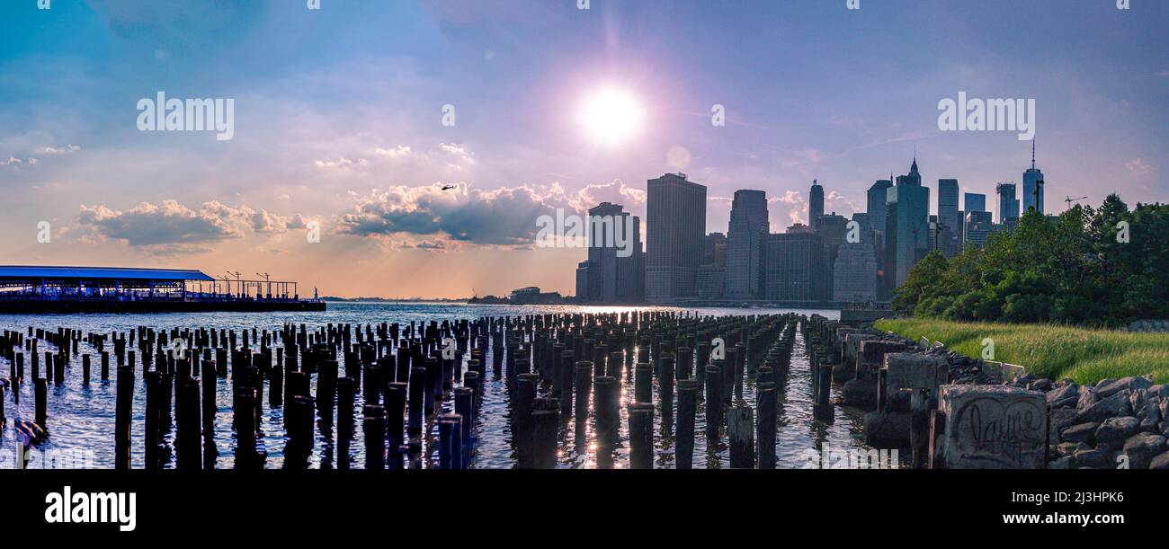 Brooklyn Heights, Nueva York, NY, EE.UU., pilares de madera en el río East visto desde el antiguo muelle 1 en Brooklyn Bridge Park. El horizonte del Bajo Manhattan en el fondo Foto de stock