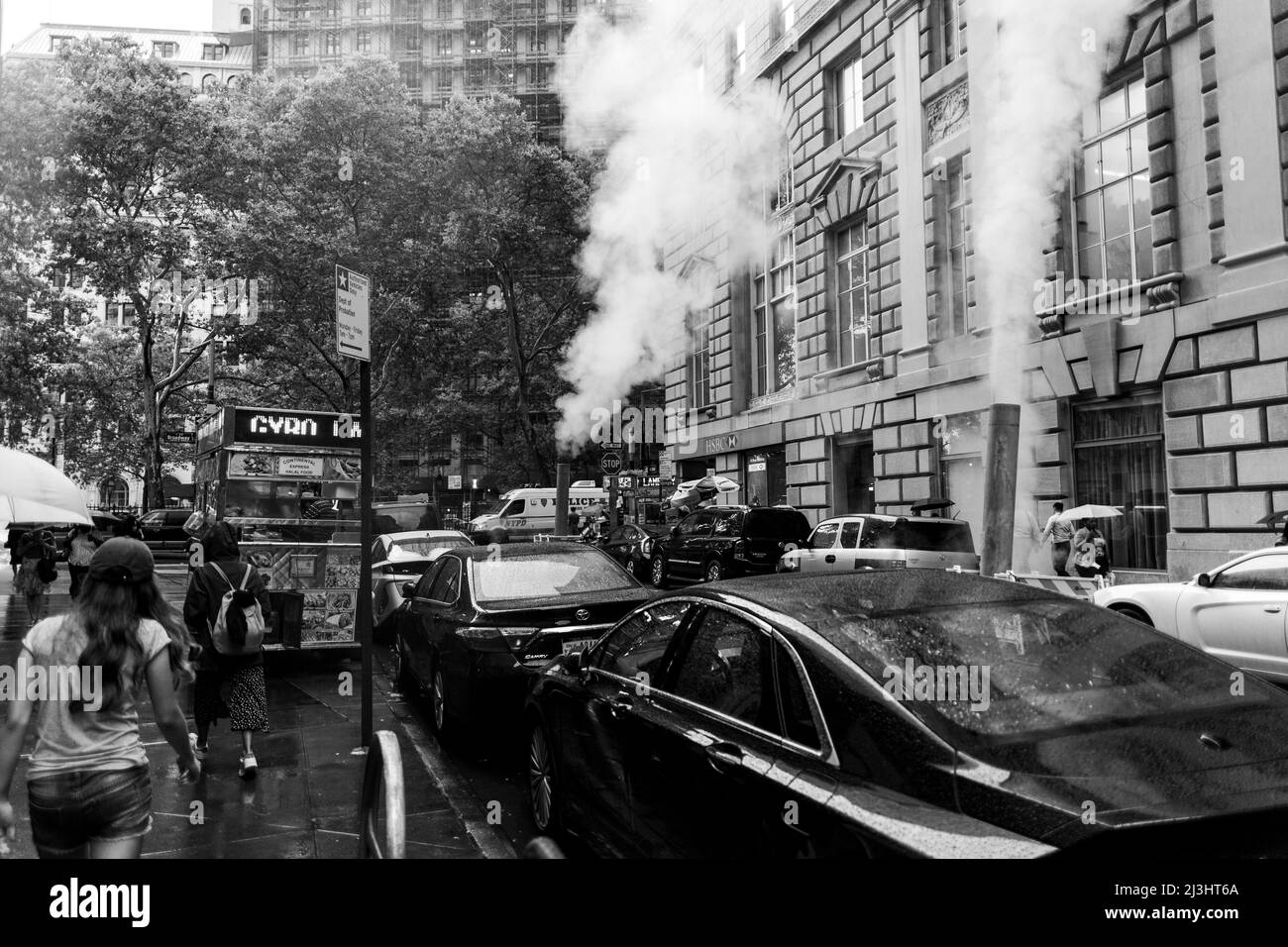 Distrito Financiero, Nueva York, NY, EE.UU., día lluvioso en Wall Street con respiradero de vapor naranja en el medio de la calle. Foto de stock