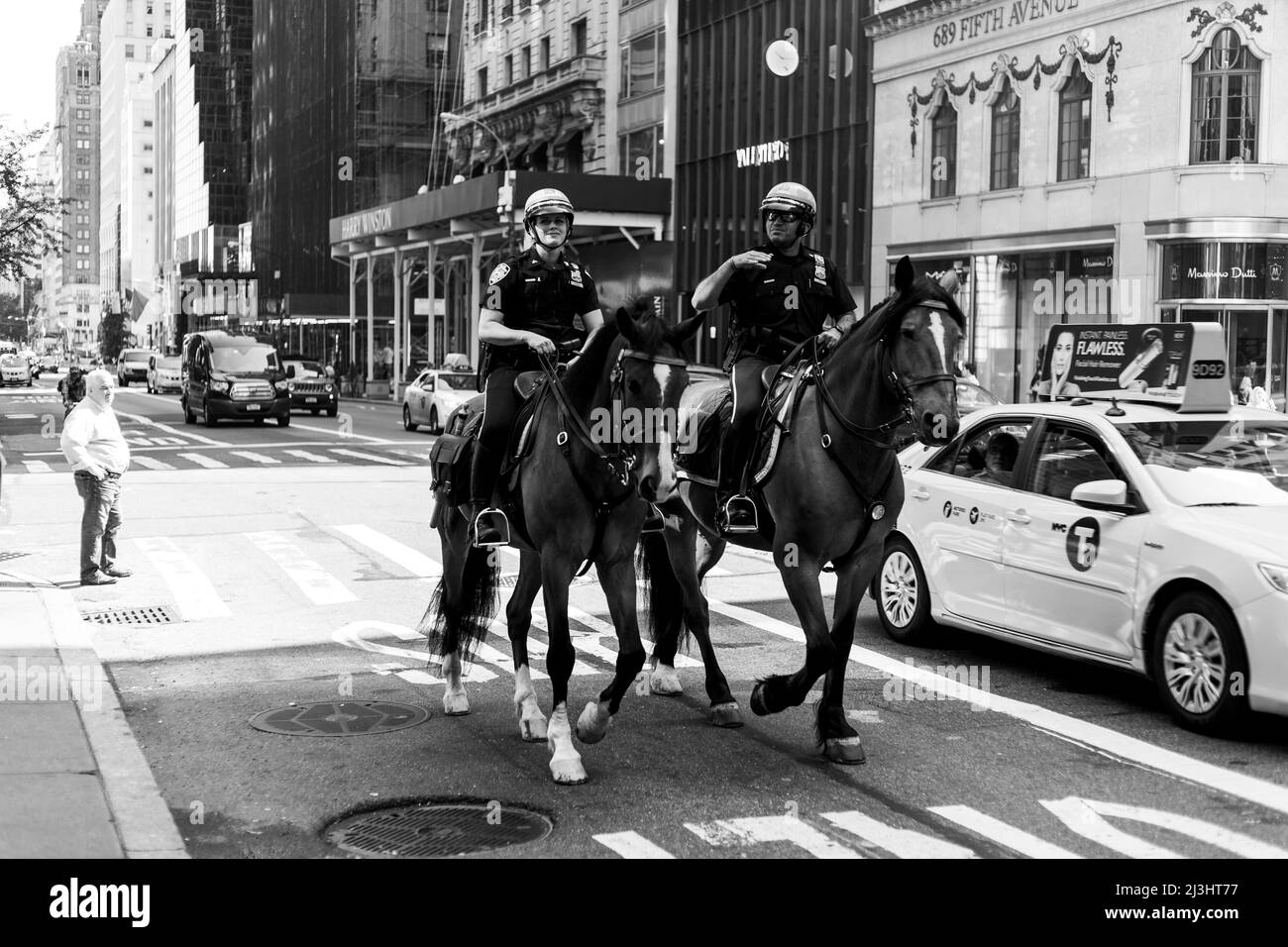 5 Ave/E 55 Street, Nueva York, NY, EE.UU., NYPD Unidad montada con dos oficiales de patrulla y caballos en servicio en la Quinta Avenida Foto de stock