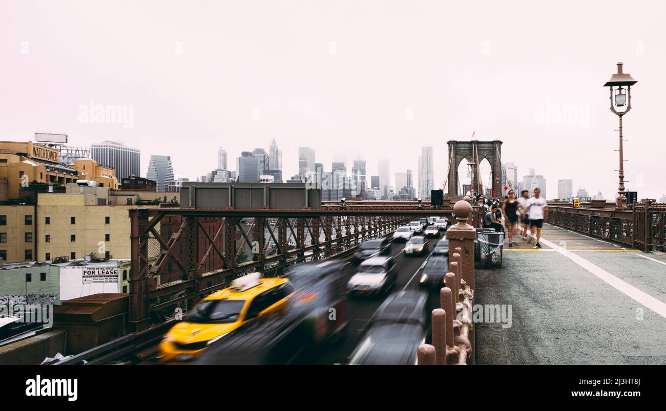 FRONT ST/York Street, New York City, NY, EE.UU., exposición prolongada con coches de conducción desde el puente de Brooklyn sobre el río East y el horizonte de Manhattan en niebla Foto de stock