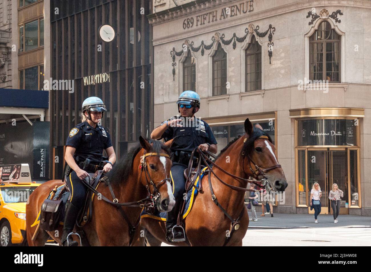 5 Ave/E 55 Street, Nueva York, NY, EE.UU., NYPD Unidad montada con dos oficiales de patrulla y caballos en servicio en la Quinta Avenida Foto de stock