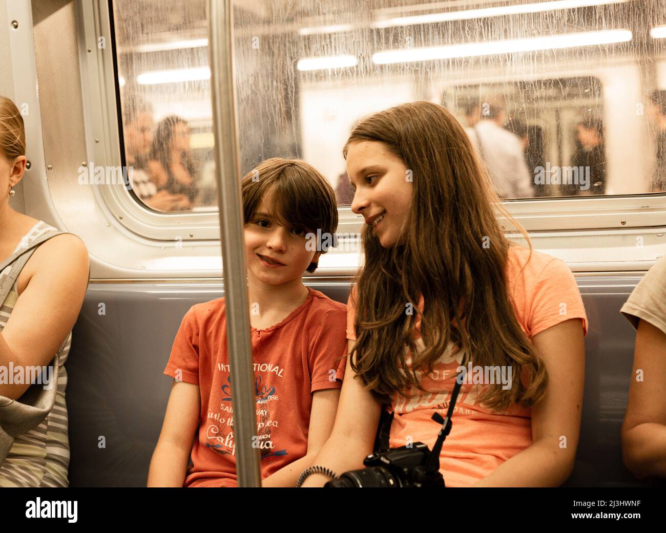 York Street, New York City, NY, EE.UU., 14 años de edad adolescente caucásico y 12 años de edad adolescente caucásico - ambos con pelo marrón y estilo de verano en un tren de metro Foto de stock