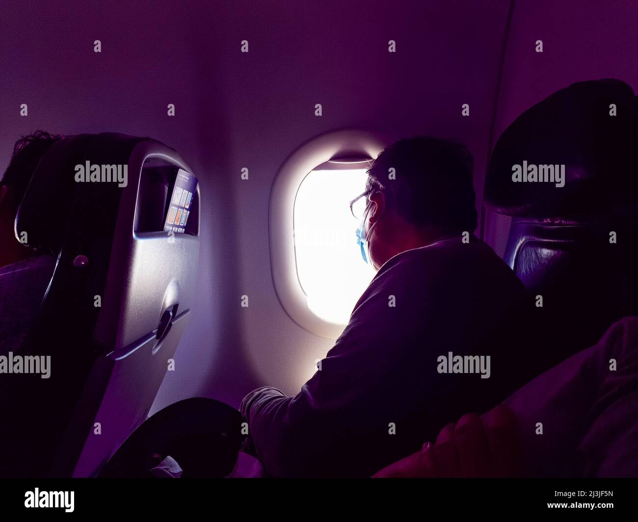 Hombre mayor mirando en la ventana a bordo de un avión durante el vuelo Foto de stock