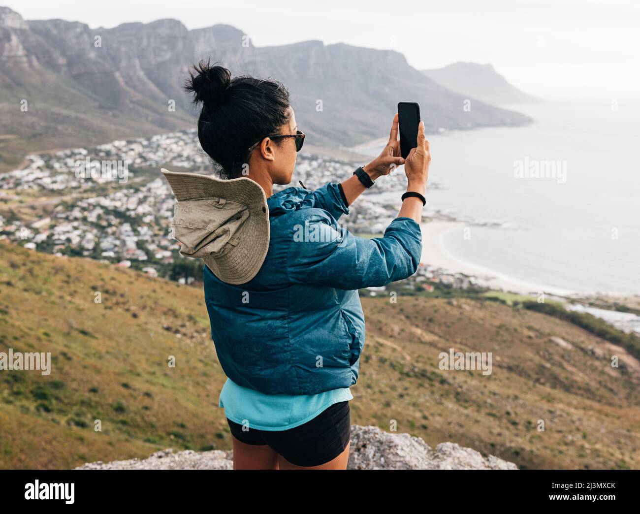 Mujer con ropa deportiva haciendo fotografías el smartphone mientras se encuentra en la cima de montaña Fotografía de stock - Alamy