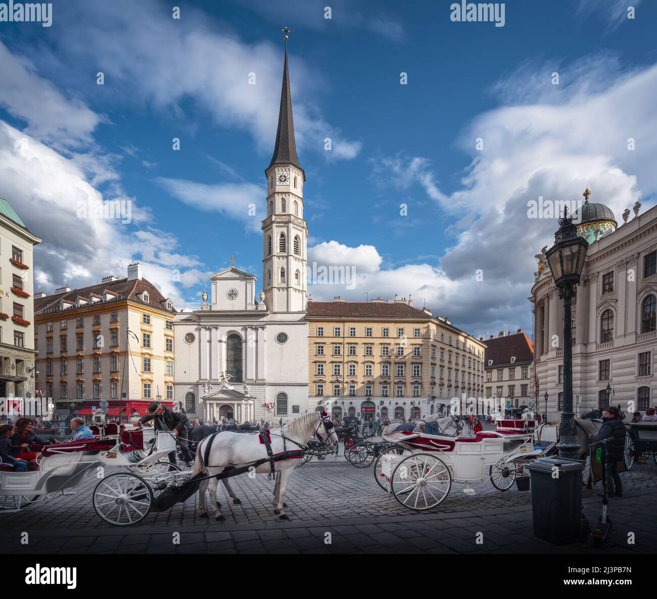 Plaza de San Miguel (Michaelerplatz) con la Iglesia de San Miguel y carruajes tirados por caballos (fiakers) - Viena, Austria Foto de stock