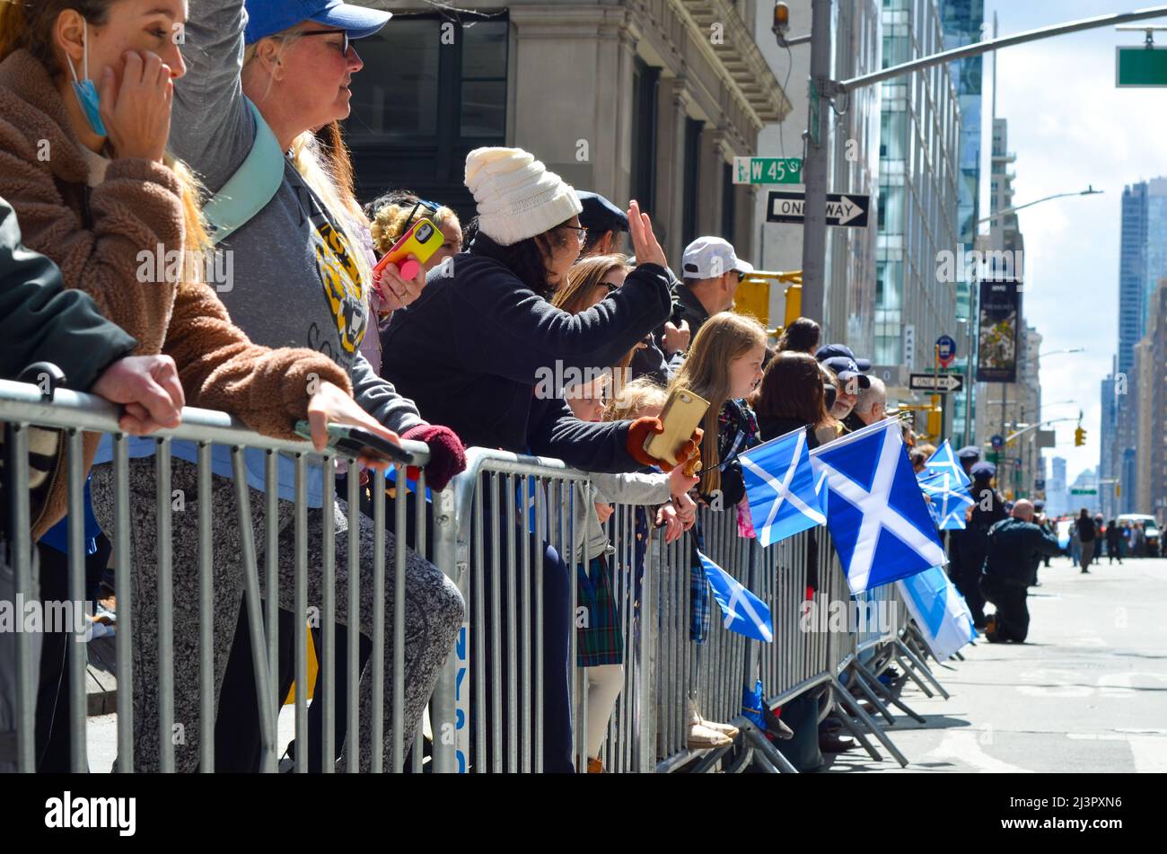 Se ve a la gente sosteniendo la bandera escocesa durante el desfile de cañerías y tambores más grande del mundo para celebrar el Día del Tartán Escocés el 9 de abril de 2022 en Nueva York, California Foto de stock