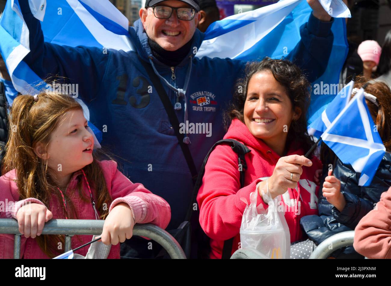 Se ve a la gente sosteniendo la bandera escocesa durante el desfile de cañerías y tambores más grande del mundo para celebrar el Día del Tartán Escocés el 9 de abril de 2022 en Nueva York, California Foto de stock