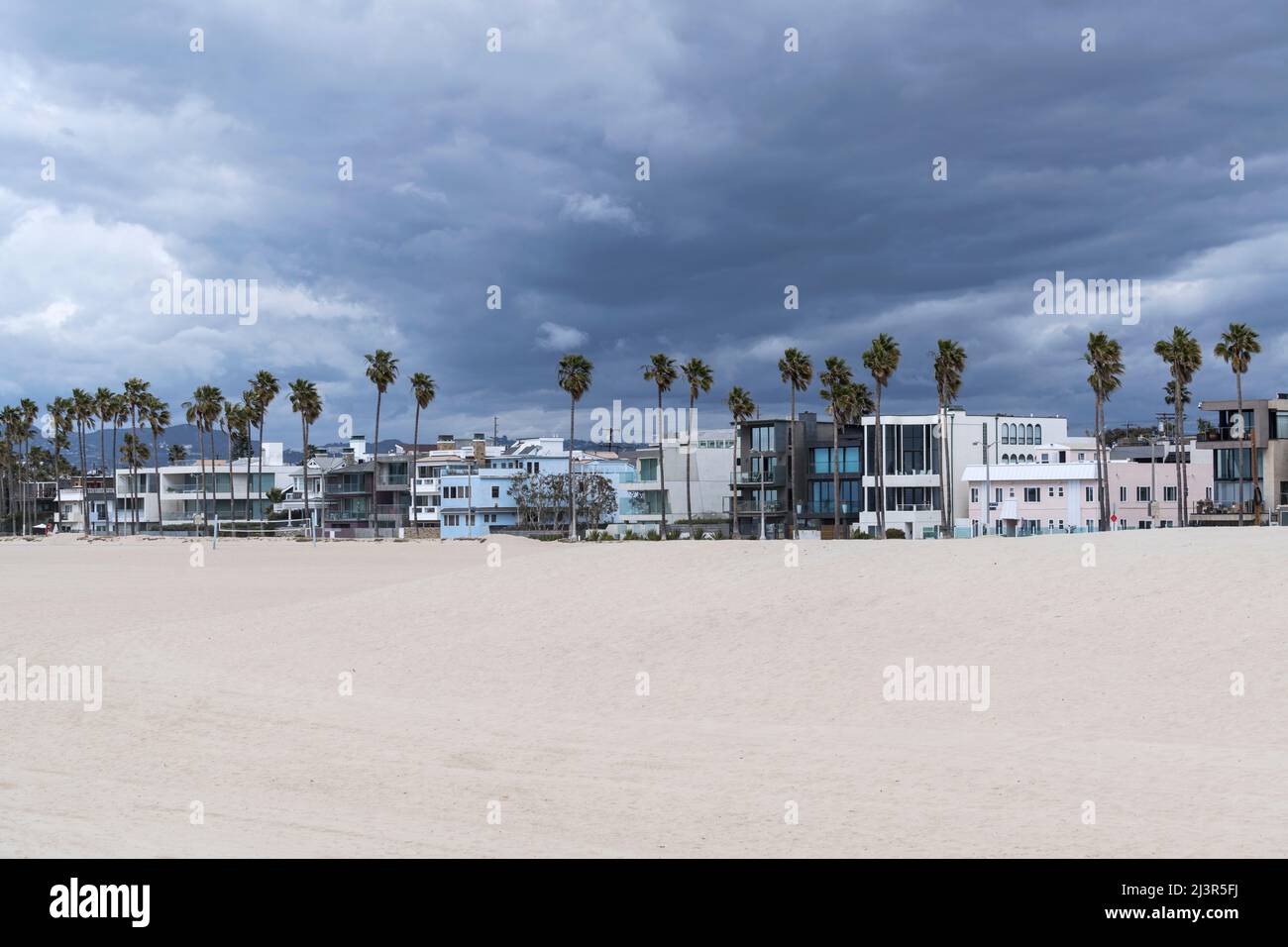Nubes de tormenta reuniéndose sobre casas y palmeras en la popular playa de Venecia en Los Angeles, California. Foto de stock