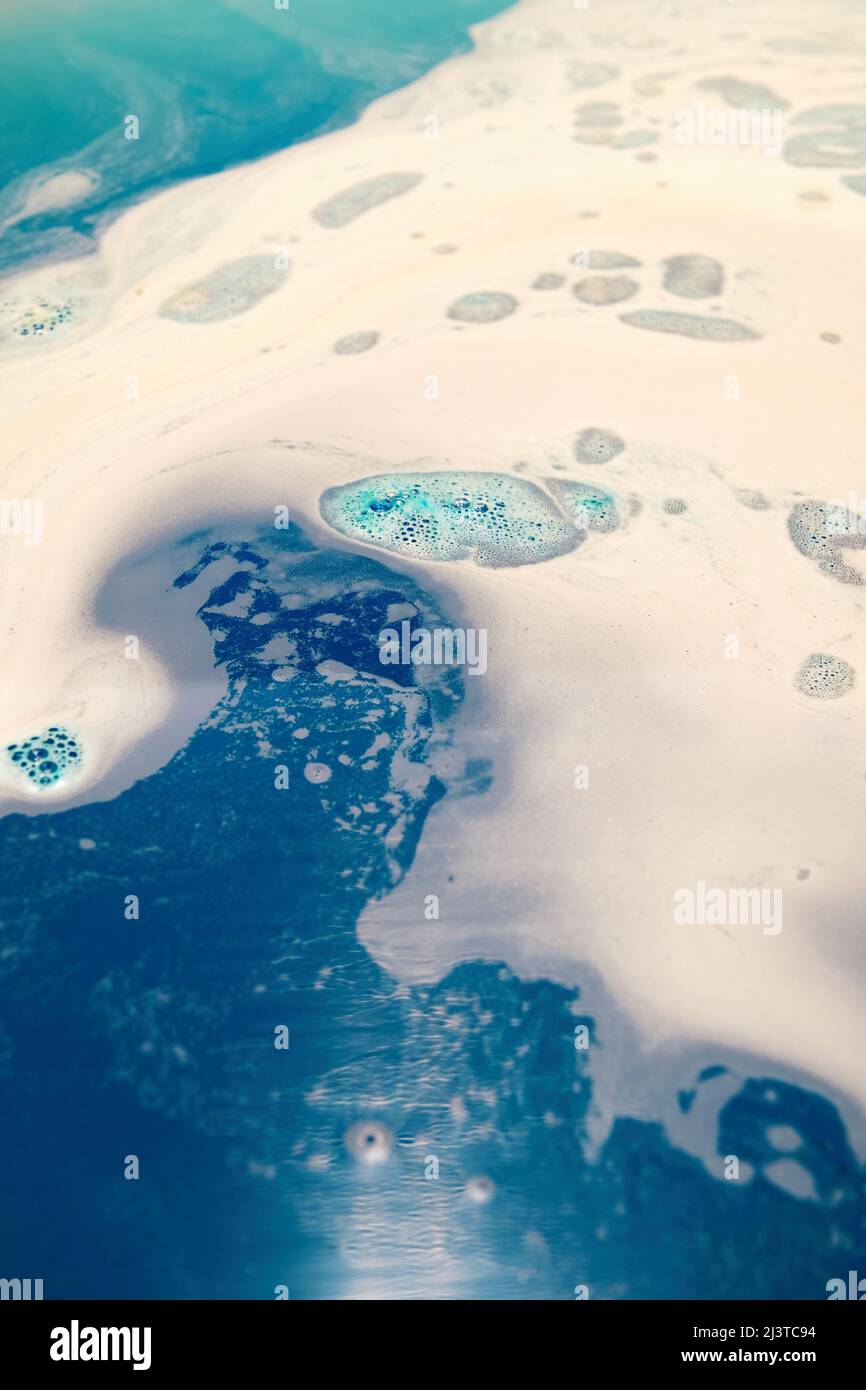 Fondo de agua caliente de baño con espuma azul y burbujas. Antecedentes de salud y cuidado corporal Foto de stock