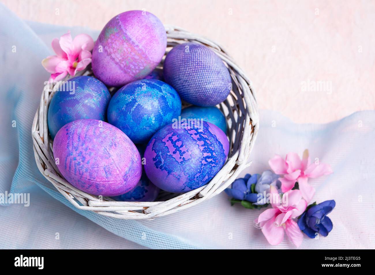 Huevos de Pascua púrpura y azul en un tazón sobre fondo pastel. Foto de stock