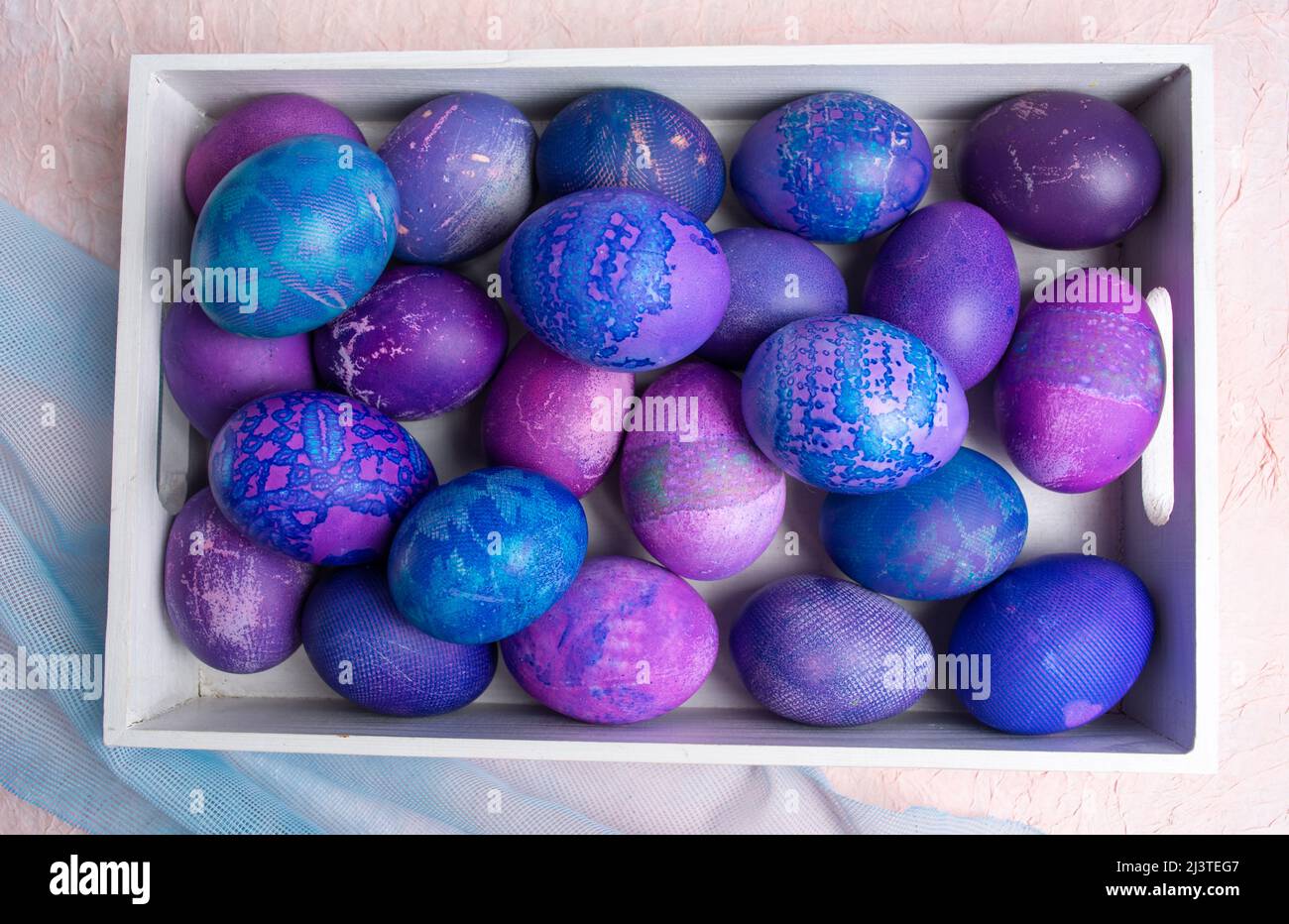Huevos de Pascua. Huevos de Pascua azul-púrpura pintados en un encaje, vista superior. Patrón de fondo de huevo. Foto de stock