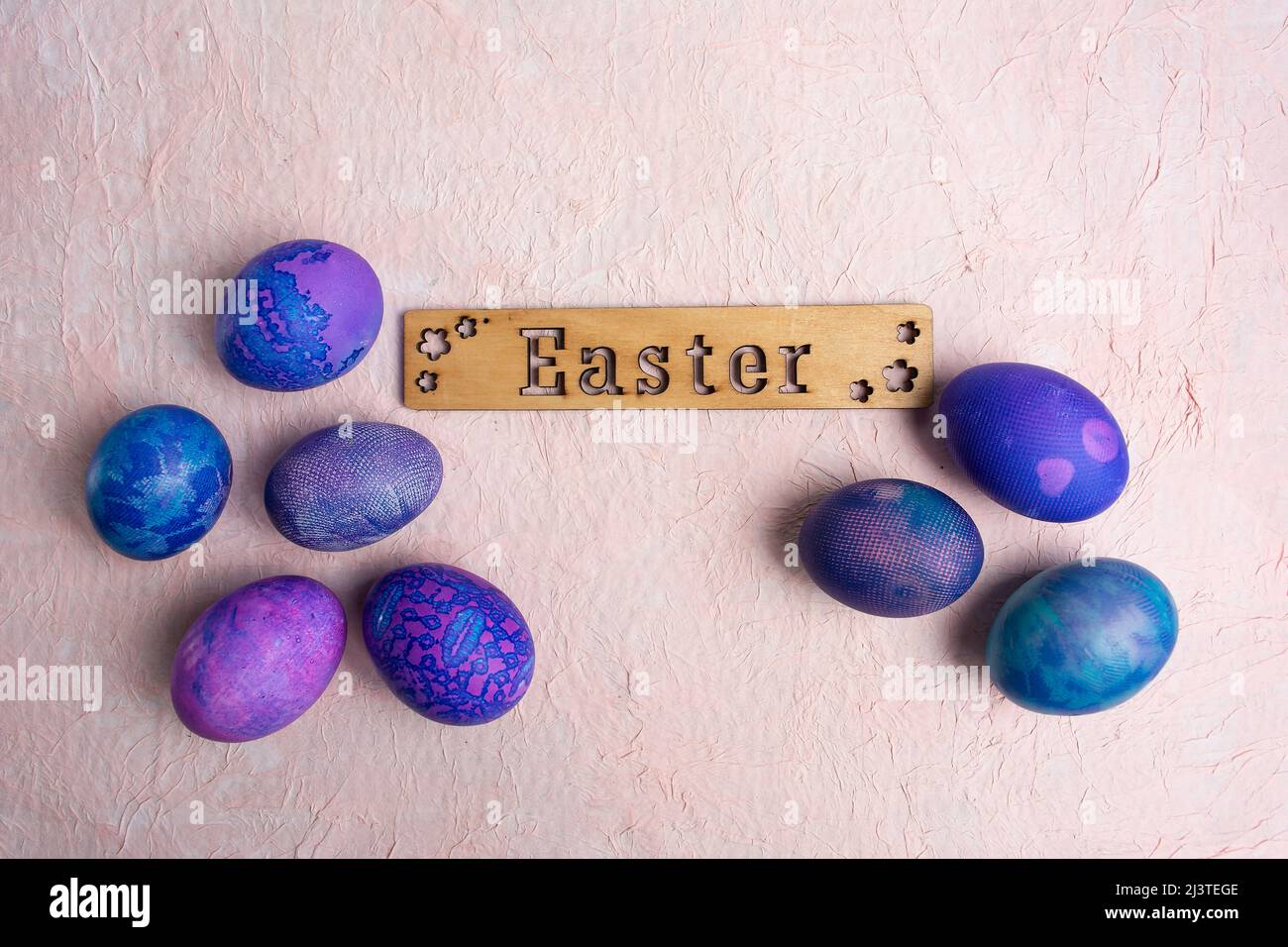 Huevos de Pascua azul púrpura con aspecto de encaje e inscripción caligráfica de Pascua sobre fondo pastel. Foto de stock