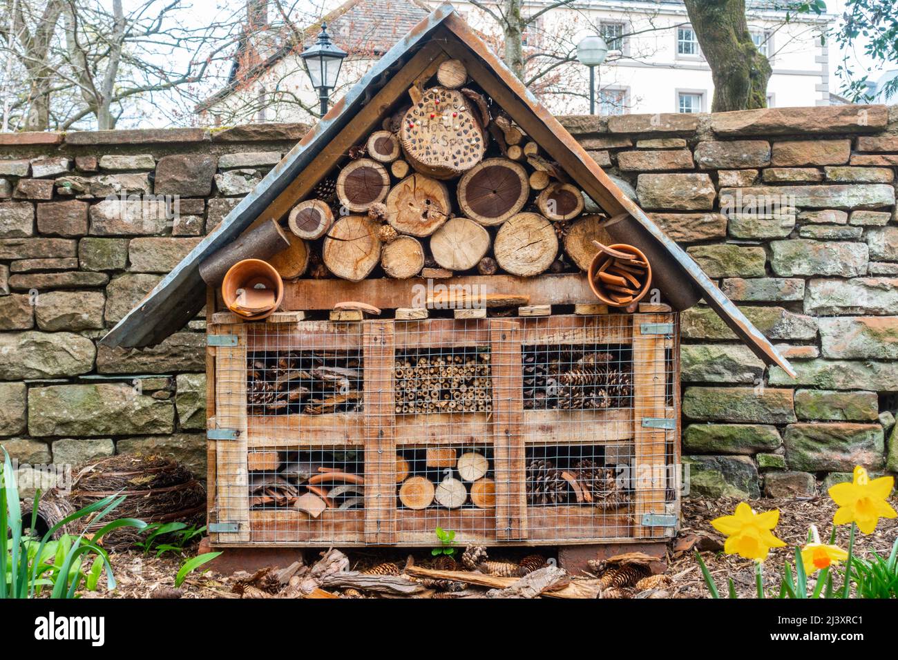Un hotel de abejas o insectos unido a un poste en un jardín para proporcionar insectos con un lugar seguro para hibernar. Foto de stock