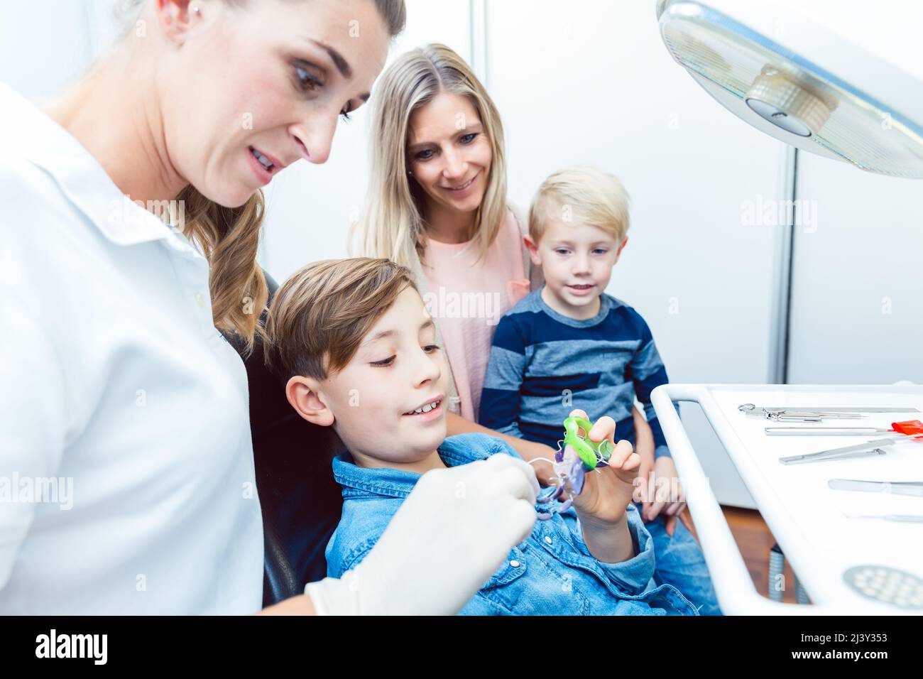 Dentista y niño paciente eligiendo los aparatos dentales en la clínica Foto de stock