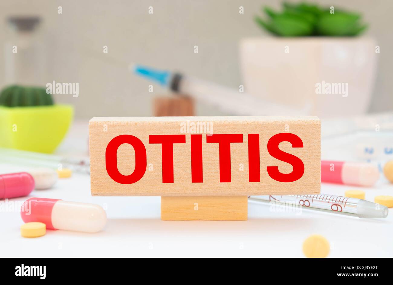 Vista superior bloques con OTITIS palabra sobre el fondo blanco con píldoras. Foto de stock