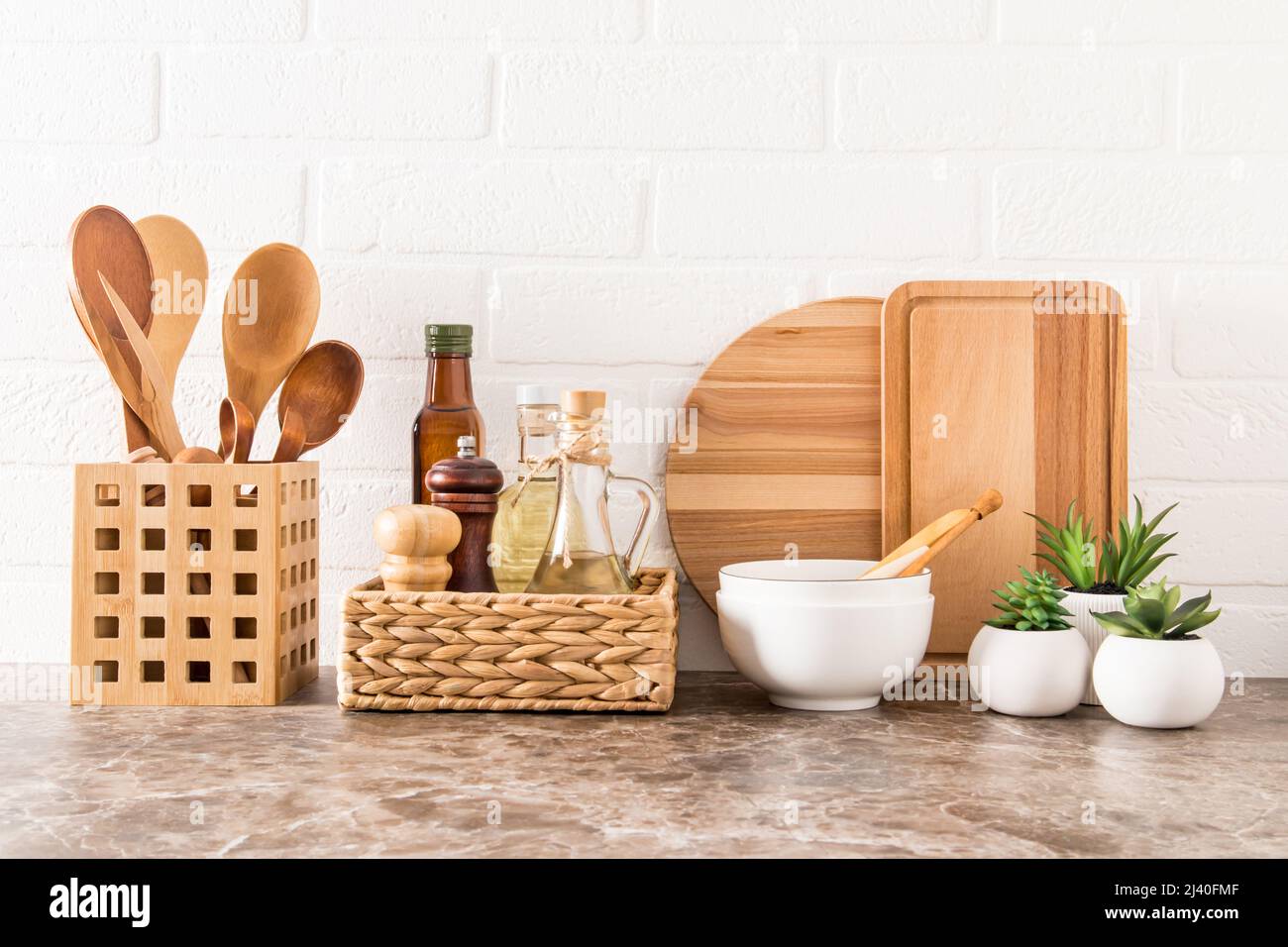 un conjunto de varios utensilios de cocina modernos en una encimera de mármol contra una pared de ladrillo blanco. materiales ecológicos sin plástico Foto de stock