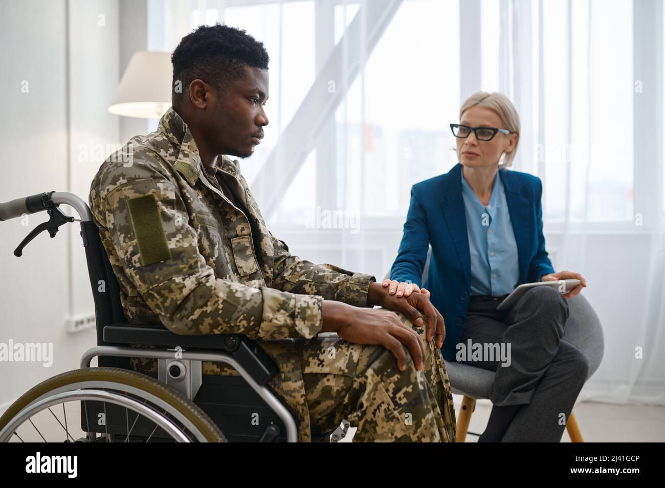 Soldado parapléjico en silla de ruedas hablando con terapeuta Foto de stock