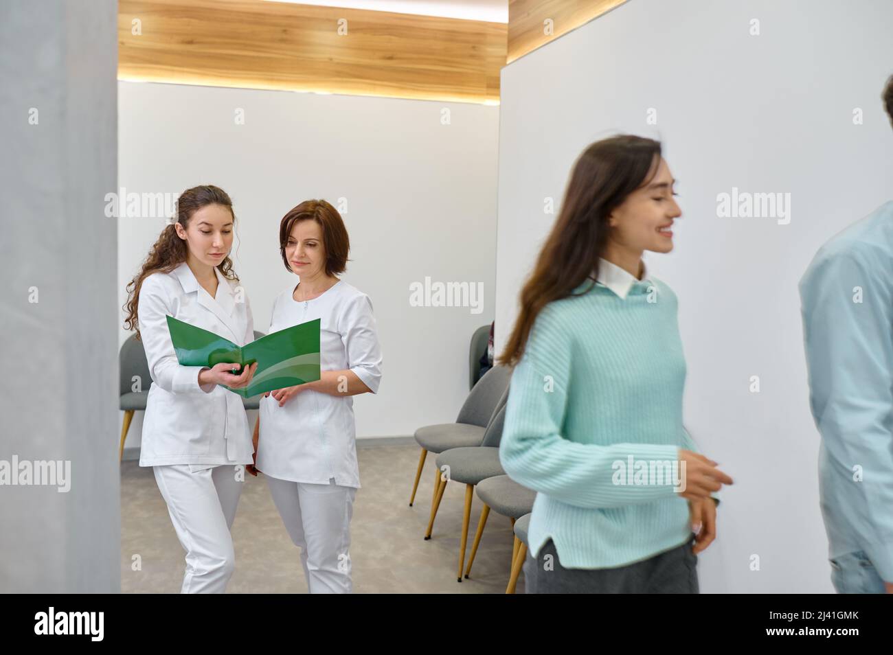 Dos enfermeras discuten el documento médico en el pasillo Foto de stock