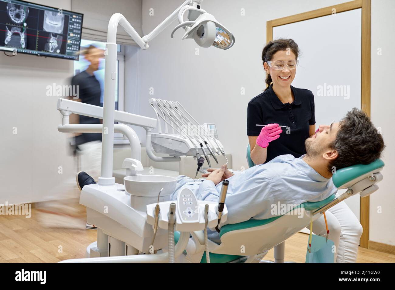 Dentista curando paciente masculino en clínica dental Foto de stock