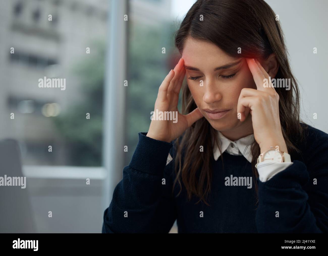 Esta migraña se siente caliente. Disparo de una joven empresaria que experimenta dolor de cabeza mientras está en el trabajo. Foto de stock