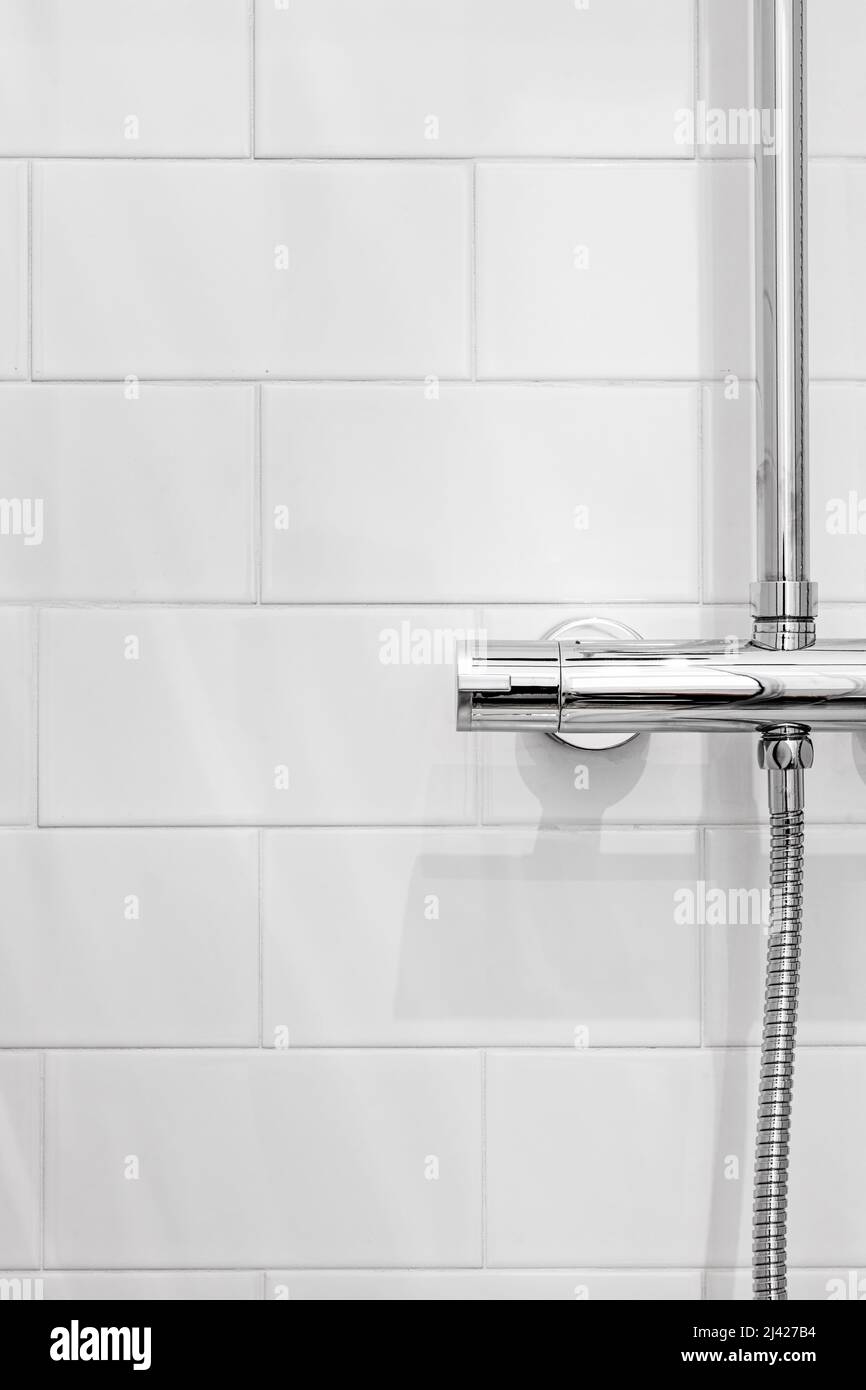 Detalle de un regulador de temperatura de cromo de una ducha con pequeñas  baldosas blancas Fotografía de stock - Alamy