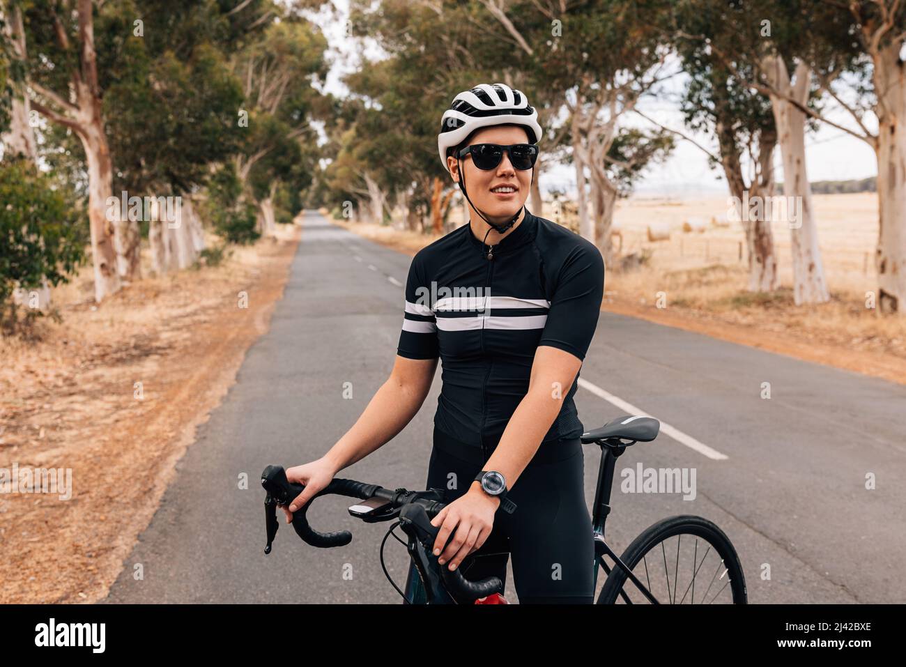 Tienda aliviar prometedor Una mujer que lleve ropa deportiva y casco de ciclismo descansando de  practicar en una carretera vacía Fotografía de stock - Alamy