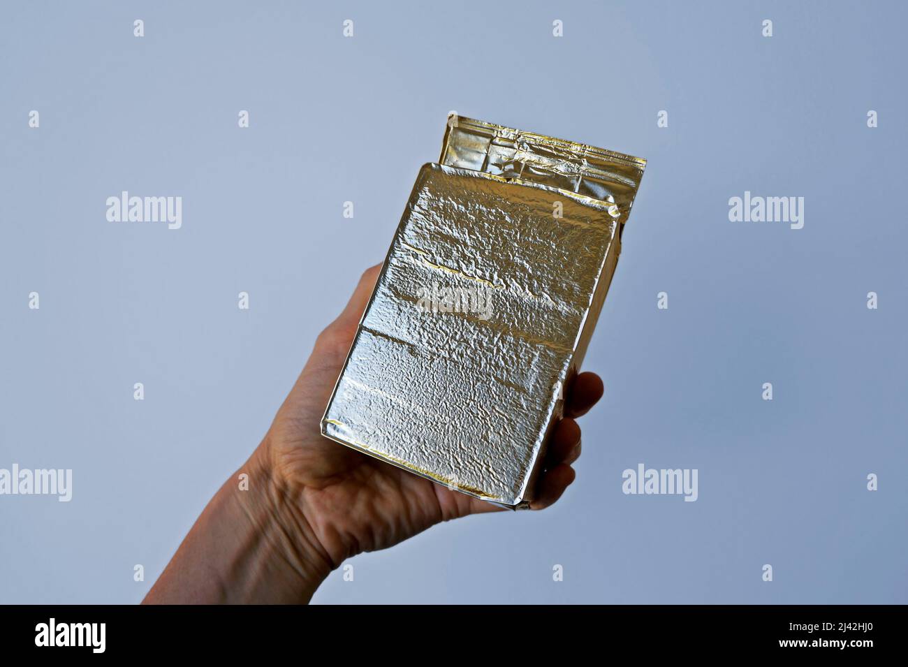 Envasado al vacío de café molido en papel de aluminio dorado a mano Foto de stock